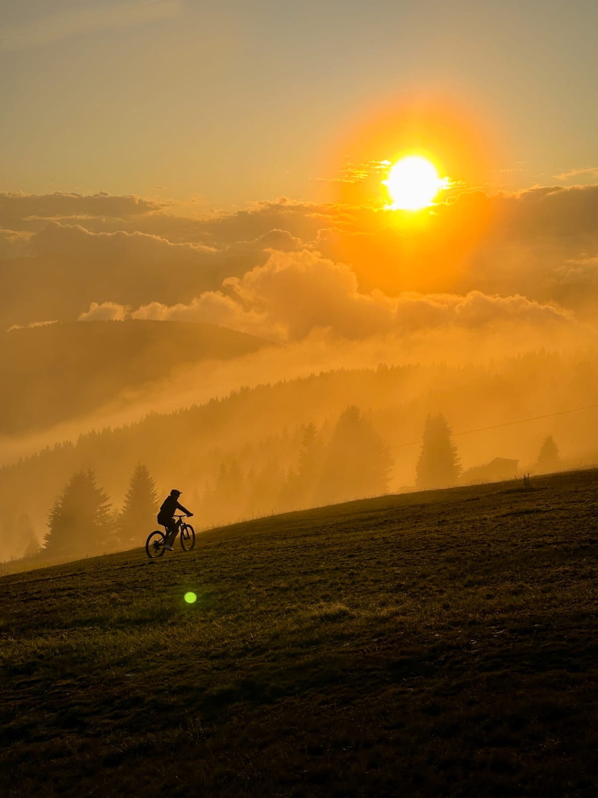Mountainbiker bei Sonnenaufgang über einer Kärntner Waldlandschaft